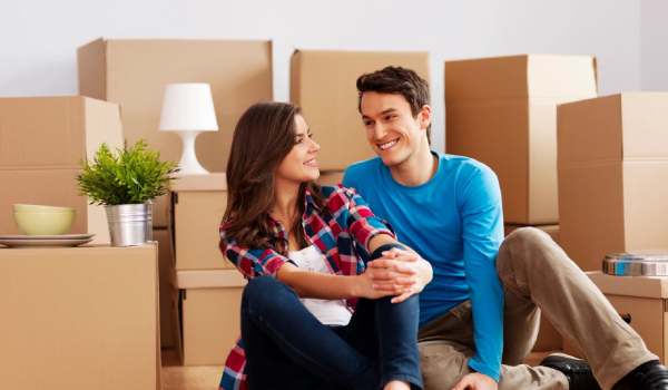 A man and woman sitting on the floor in front of boxes.